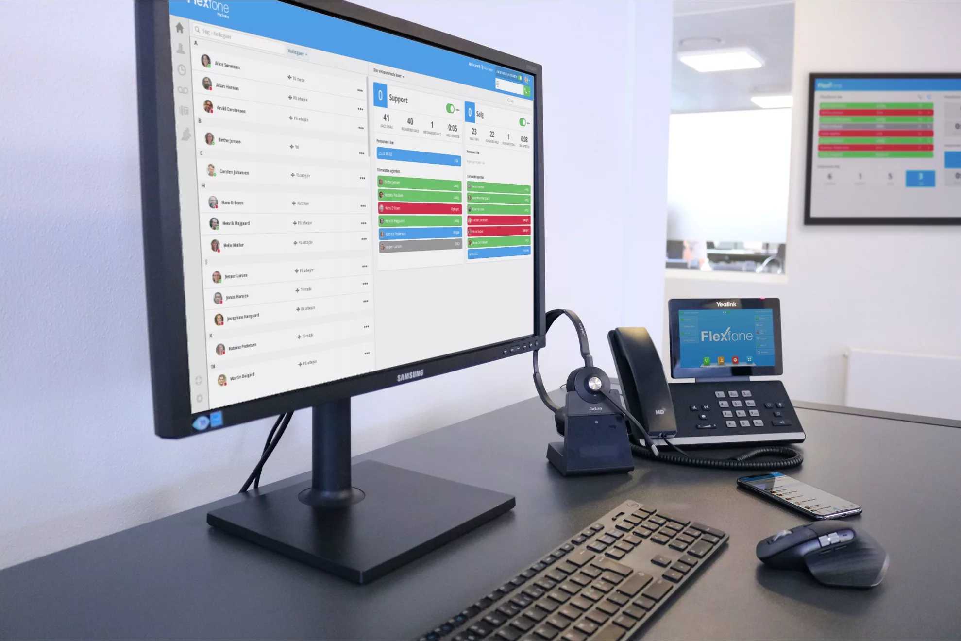 Kontorbord med tændt pc skærm og telefon